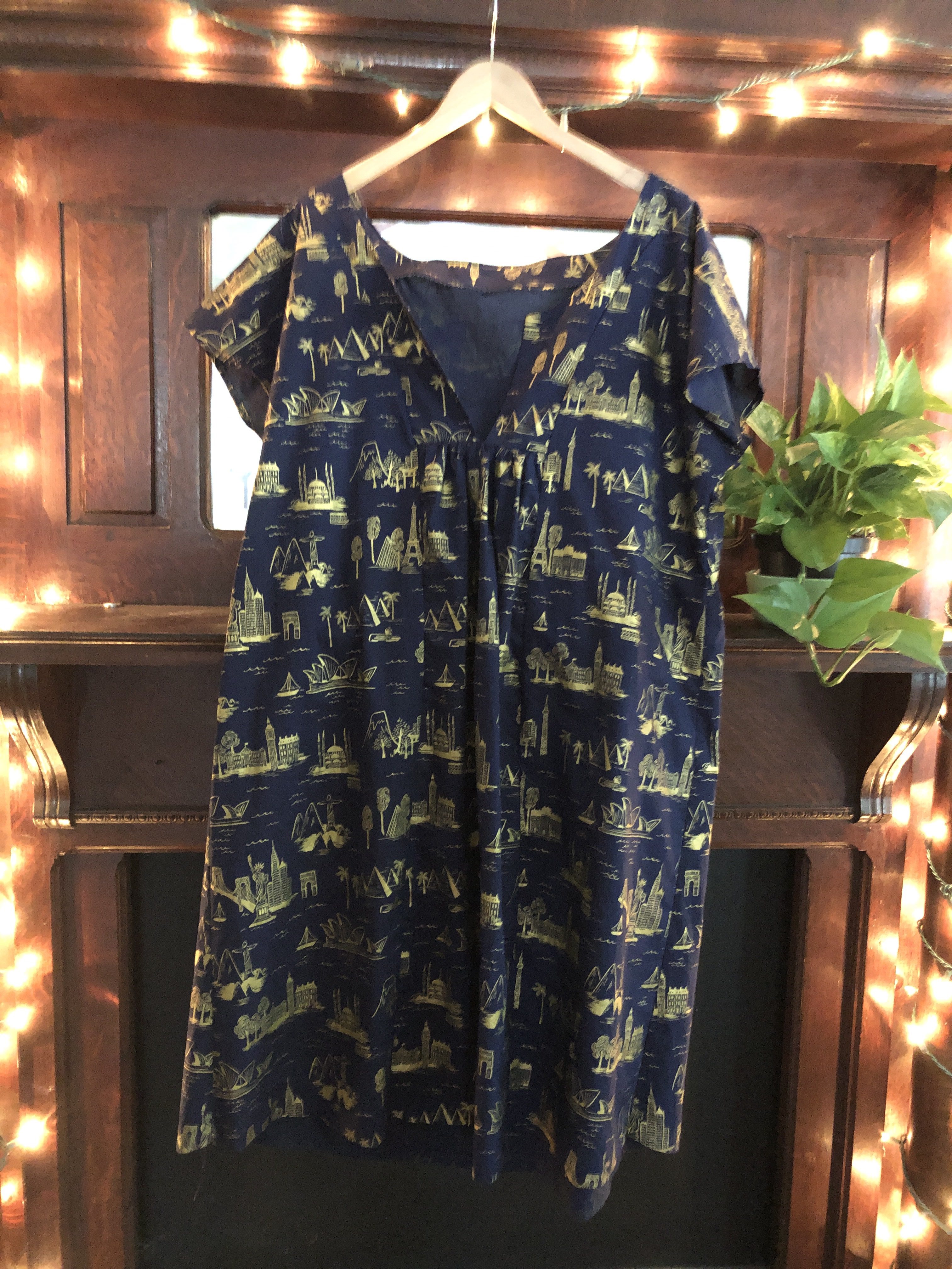 Photo of a Mojave dress from Seamwork. The fabric is dark blue with gold silhouettes of landmarks printed on it.