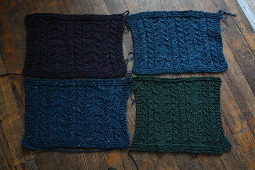 Photo of four swatches of the same cable patterns, worked in different yarns to check gauge.