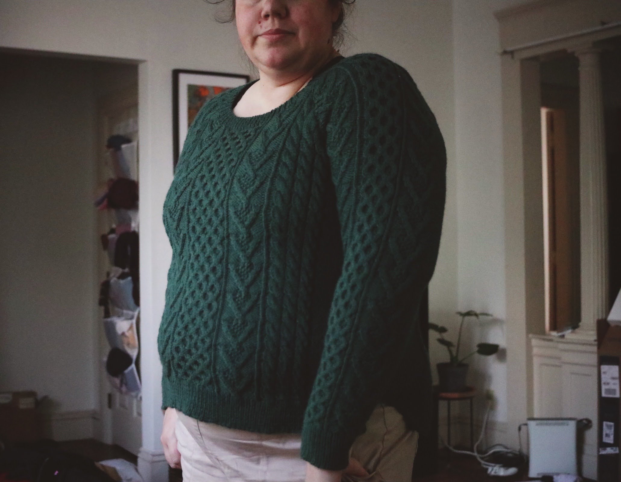 Small-fat woman is modeling a green cabled sweater