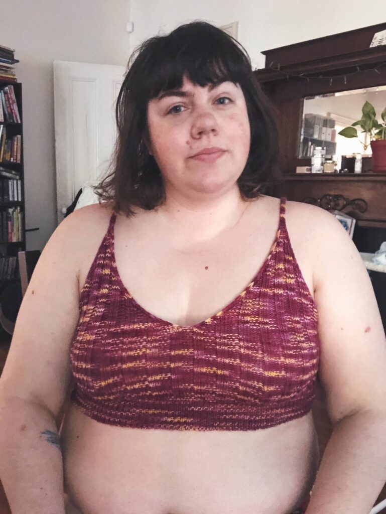 Photo of Amy wearing her Ripple Bralette, knit in purple with some gold specks