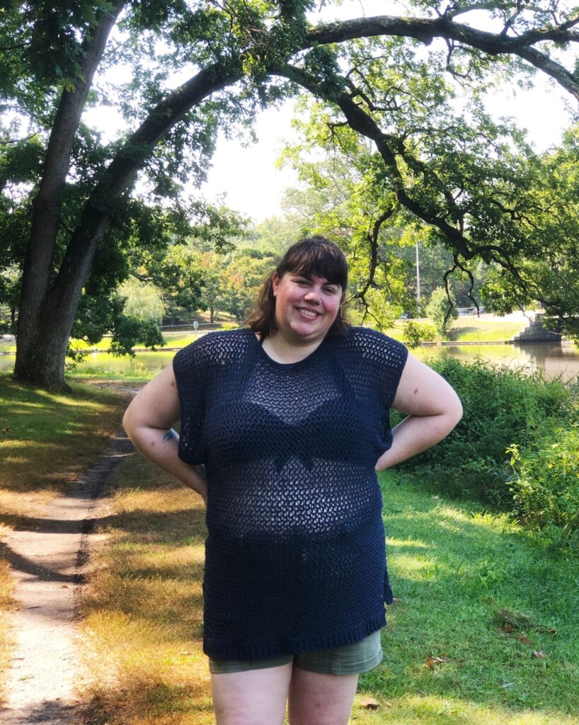 Photo of Amy, a small fat white woman, wearing a dark blue crocheted Summertime Tee designed by Toni Lipsey