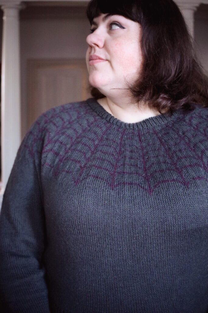 photo of Amy modeling her Arachne sweater, in which she used the ladder back jacquard technique to work the long colorwork float sections