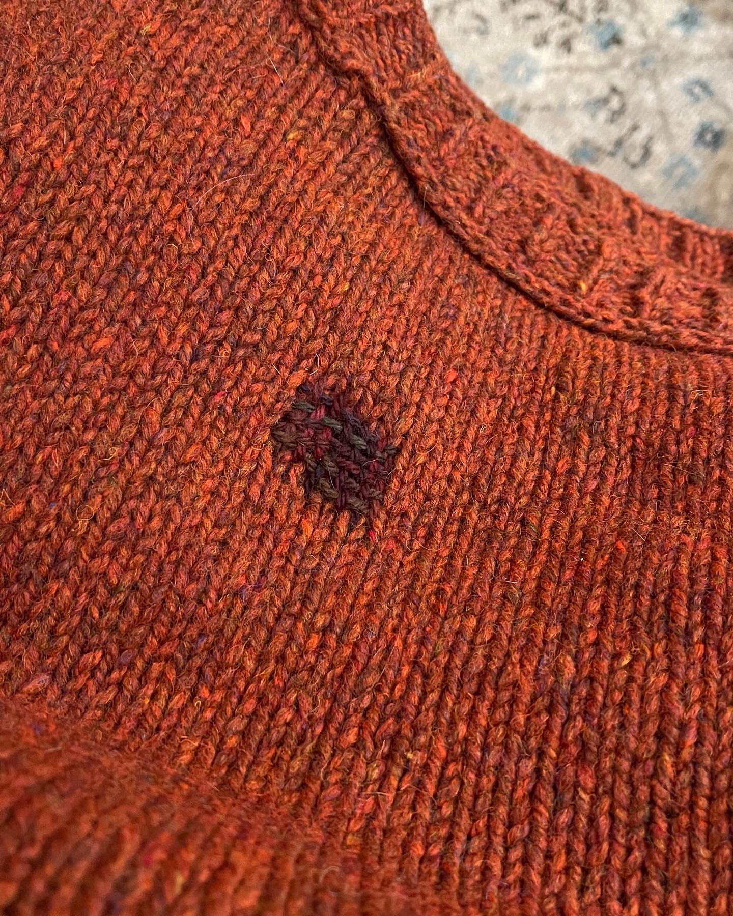 Visible mending on a sweater using dark yarn