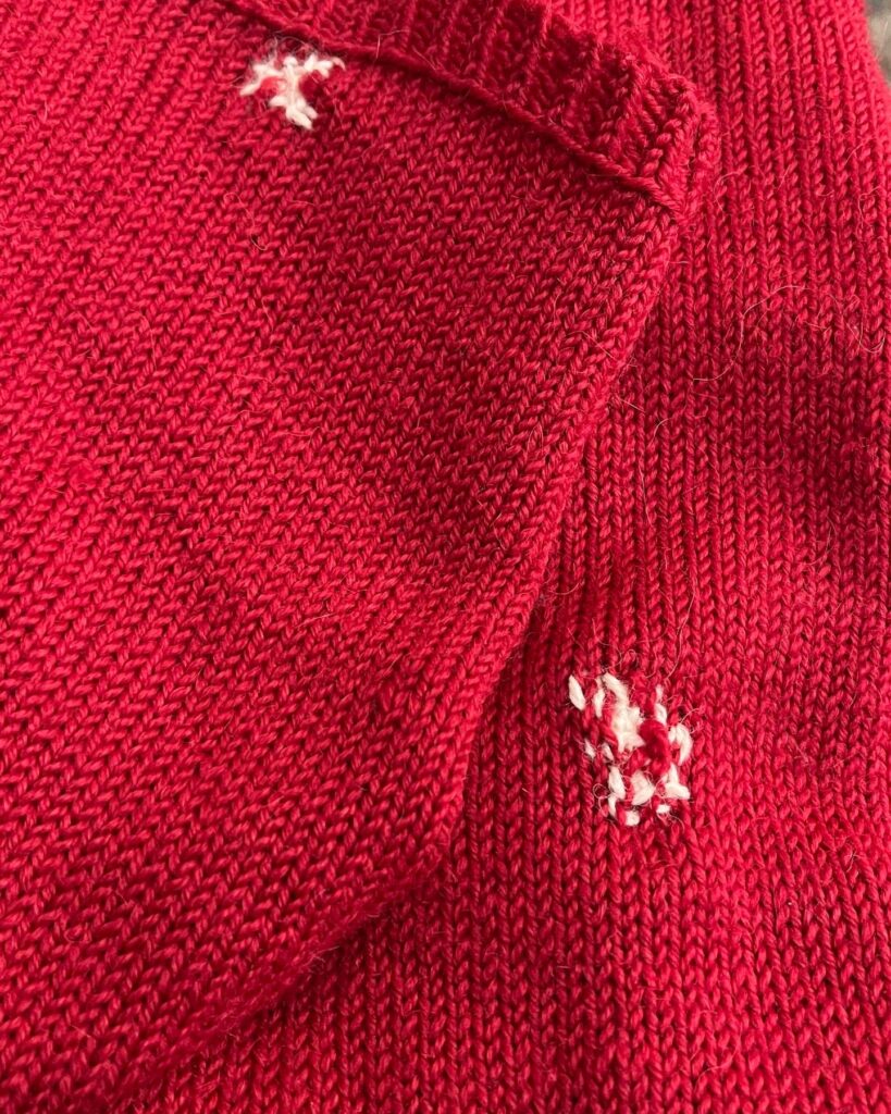 Visible mending on knitted cardigan sleeves